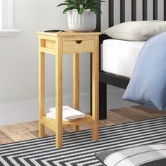 a small wooden table sitting on top of a bed next to a white and blue pillow