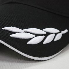 a black and white baseball cap with leaves embroidered on it