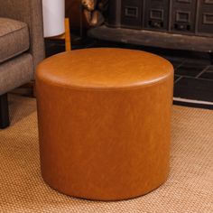 a tan leather ottoman sitting on top of a rug in front of a fire place