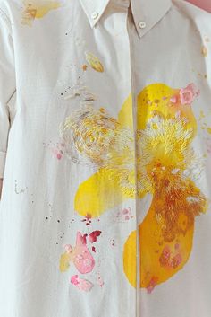 a white shirt with yellow and pink flowers painted on it