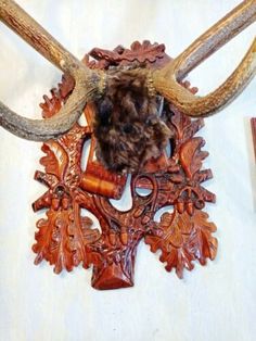 an animal's head is mounted on the wall next to some wood carvings and pens