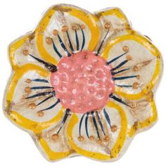 a yellow and white flower shaped object with beads on it's center, against a white background