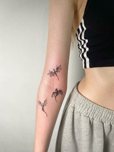 a woman's arm with three small dragon tattoos on her left arm and the other arm