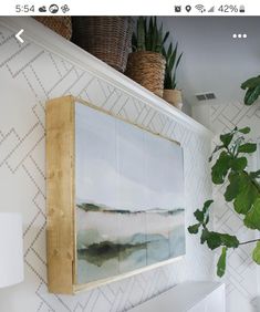 a painting hanging on the wall next to a potted plant