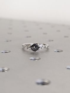 a diamond ring sitting on top of a silver surface with drops of water around it