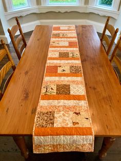 a wooden table topped with an orange and brown patchwork table runner