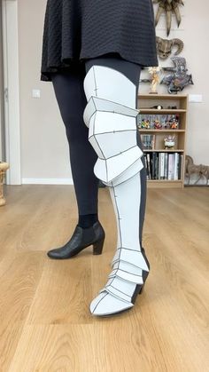 a woman in black and white boots standing on top of a wooden floor next to a book shelf