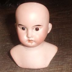 a small doll head sitting on top of a wooden table