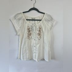 Lucky Brand Embroidered Short Sleeved Top Size Small Boho, Romantic Nwt, Retail $79.50 This Top Is White Cotton And Features Beautiful Beige Embroidery On The Front, Button Up Front, Short Sleeves, And Is Lightweight. A Lovely Top For Warm Weather. Feminine Embroidered White Tops, Cream Tops With Floral Embroidery, Elegant Floral Embroidery Top For Vacation, Elegant Floral Embroidered Top For Vacation, Casual Cream Top With Floral Embroidery, Casual Cream Floral Embroidered Top, Casual Cream Embroidered Top With Floral Design, White Short Sleeve Embroidered Top For Daywear, White Feminine Embroidered Cotton Top