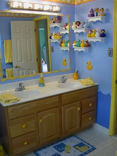 a bathroom with blue walls and yellow accessories on the sink counter, along with shelves that have rubber ducks