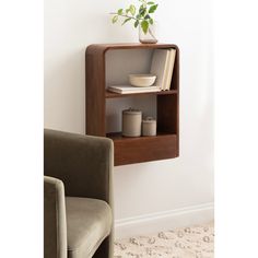 a wooden shelf with two books and a vase on it, next to a chair