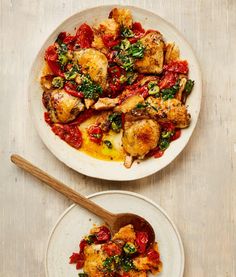 two white plates with food on them and a wooden spoon next to one plate that has chicken, tomato sauce, and spinach