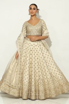 Ivory and gold kalidar lehenga with all over Padma bagh motif embroidery using zardozi highlights and tassel ornamentation. Paired with an elbow sleeves floral jaal embroidered leaf neck blouse with dangling glass beads hem and a bloom border embroidered dupatta. - Aza Fashions White Resham Embroidery Lehenga For Ceremonial Occasions, White Ceremonial Lehenga For Diwali, White Lehenga For Diwali Ceremonial, White Lehenga For Ceremonial Occasions During Diwali, White Lehenga For Ceremonial Occasions And Diwali, Gold Semi-stitched Lehenga With Dabka Detailing, Gold Embellished Lehenga In Dola Silk, White Ceremonial Lehenga For Navratri, Embroidered Cream Lehenga Unstitched