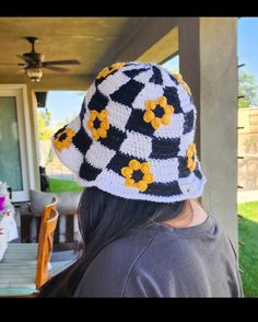 a woman wearing a black and white crocheted hat with yellow flowers on it