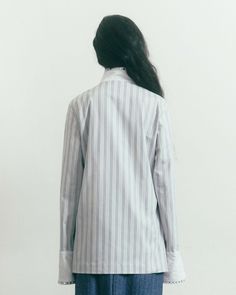 a woman standing in front of a white wall with her back turned to the camera