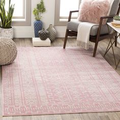 a pink area rug in a living room with two chairs and potted plants on the floor