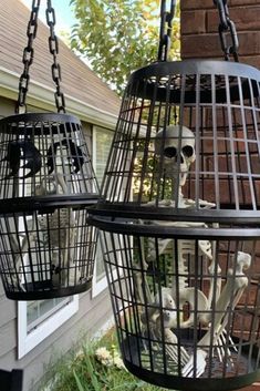 two bird cages with skeletons in them hanging from chains