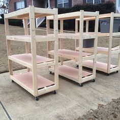 three wooden shelvings sitting on top of a cement ground next to a brick building