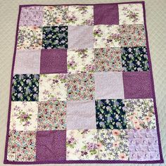 a purple and white quilt with flowers on it