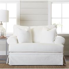 a white couch sitting next to a lamp on top of a table