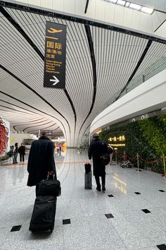 two men with luggage walking through an airport