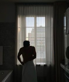 a man standing in front of a window next to a bath tub