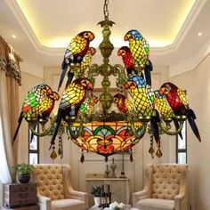 a chandelier hanging from the ceiling in a living room with chairs and tables