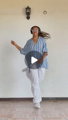 a woman is dancing on the floor with headphones in her ears and wearing white pants