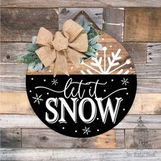 a black and white sign that says let it snow on the front of a wooden wall