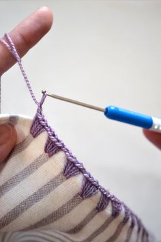 someone is crocheting the stitchs on a sweater with a blue knitting needle