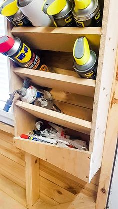 a wooden shelf filled with lots of spray cans