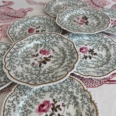 five plates with pink flowers on them are sitting on a tablecloth covered table cloth