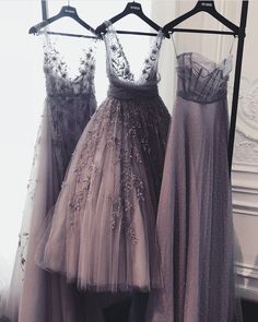 three dresses are hanging on a rack in front of a window and one is wearing a dress with flowers