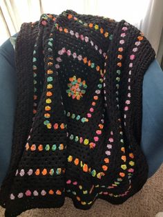 a black crocheted blanket sitting on top of a blue chair