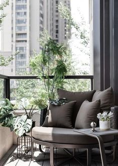 a balcony with some plants on it and a chair in the foreground, next to a coffee table