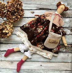 a doll is laying on the ground next to some pine cones