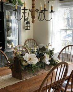 a dining room table is decorated with flowers and greenery for the centerpieces