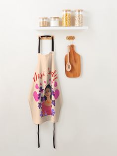 an apron hanging on the wall next to a cutting board and utensil holder