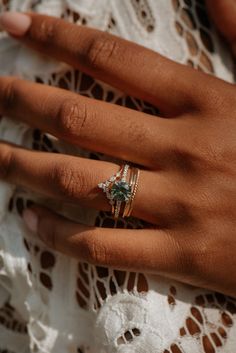 a close up of a person's hand with a ring on their finger and an emerald colored stone in the middle