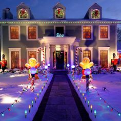 christmas decorations in front of a large house with candy canes on the ground and lights all around