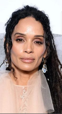 a close up of a person with long hair wearing earrings and a sheer top on