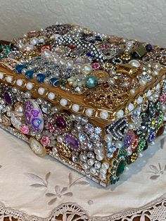 an elaborately decorated box sitting on top of a doily with lace and beads