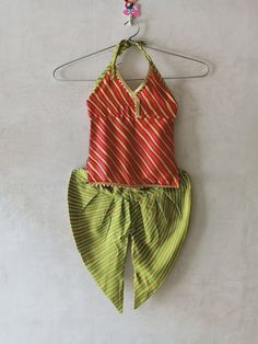 an orange and green swimsuit hanging on a hanger next to a white wall