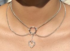 Layered chain, choker-style necklace with heart charm center! Can be extended up to one inch. Model is wearing a 13 in. necklace. Trendy Heart-shaped Metal Choker, Trendy Heart Shaped Metal Choker, Metal Heart Pendant Choker, Trendy Silver Heart-shaped Choker, Heart Charm Metal Choker With Heart Pendant, Metal Heart Charm Choker With Heart Pendant, Metal Heart Pendant Choker With Heart Charm, Metal Choker With Heart Charm And Pendant, Trendy Metal Choker With Heart Pendant