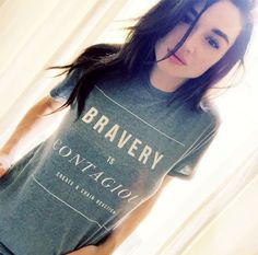 a woman with long hair wearing a t - shirt that says brauery is contagion