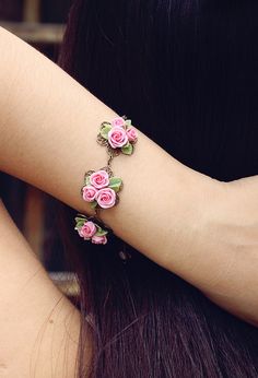 a woman wearing a bracelet with pink roses on it