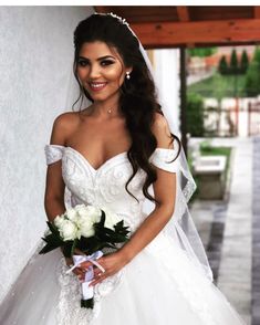 a woman in a wedding dress is posing for the camera with flowers on her bouquet