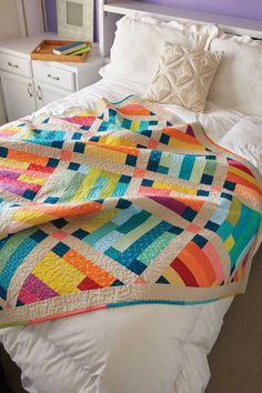 a bed with a colorful quilt on top of it