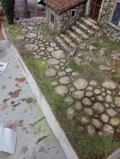 an old house with stone steps and grass growing on the roof, next to a building