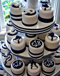 a triple layer cake with blue and white fondant decorations on the bottom tier is decorated with an anchor